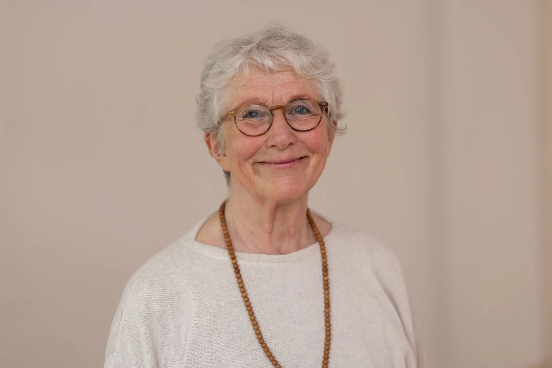 Lächelnde Frau mit Brille und weißem Haar.