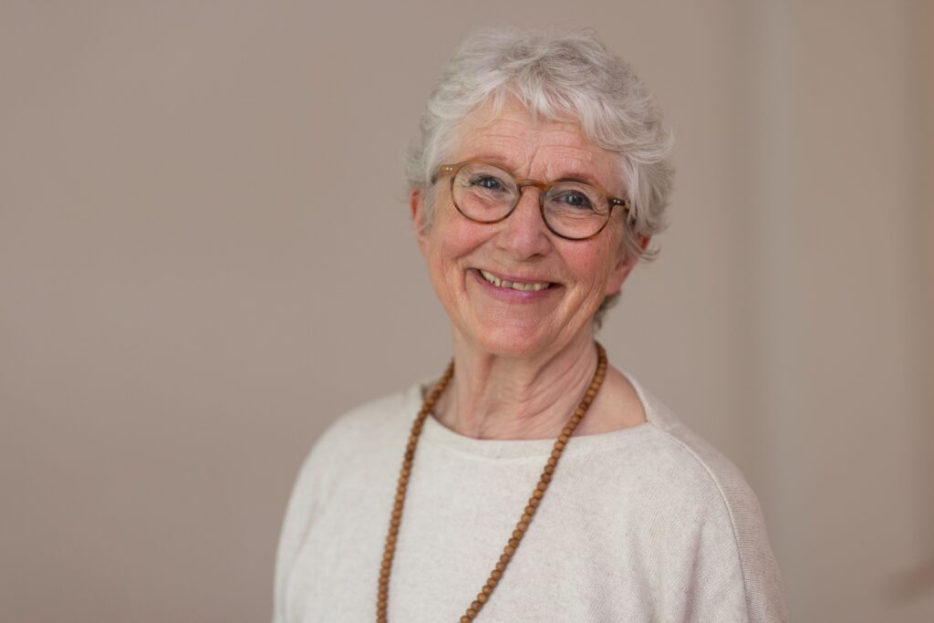 Lächelnde Frau mit Brille und weißem Haar.